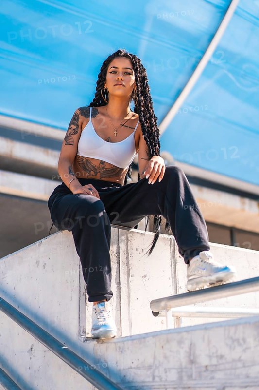 Young woman of black ethnicity with long braids and with tattoos