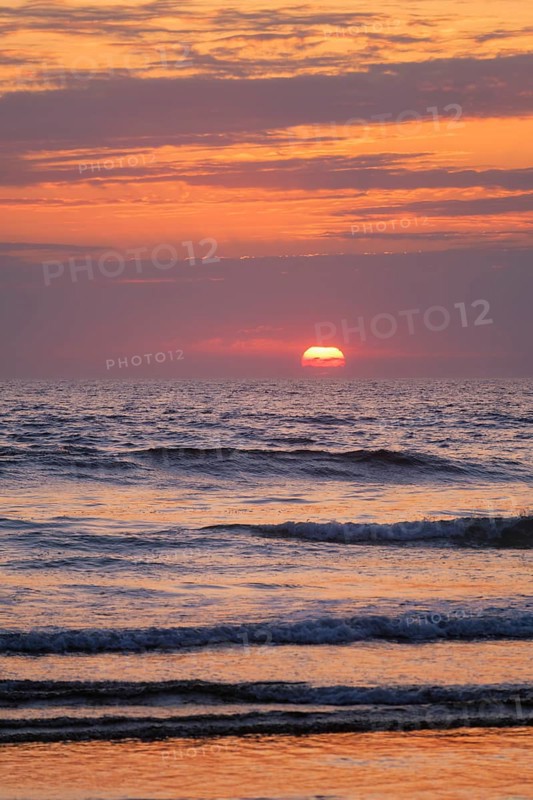 Ocean waves on sunset with setting sun background
