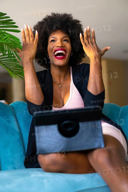 Young entrepreneur of black race and afro hair making a video call with great joy and amazement
