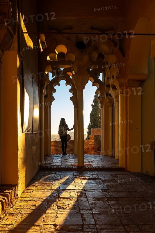 A young woman at sunset from the Arab doors of a courtyard of the Alcazaba in the city of Malaga