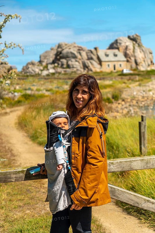 A young girl with her baby visiting the house among rocks by the sea