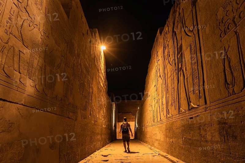 Un joven turista en los pasillos a la noche del templo de Kom Ombo con el traje tradicional