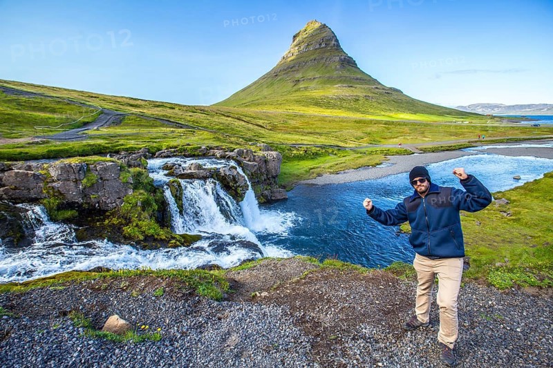 A boy in the famous Icelandic mountain Kirkjufell and the small waterfalls