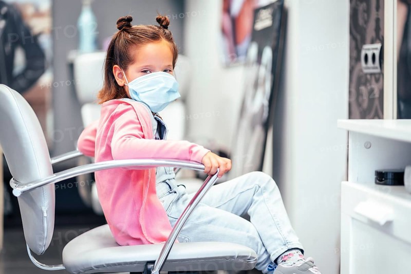 Girl sitting on the chair with pigtails finished. Reopening with security measures for hairdressers in the Covid-19 pandemic