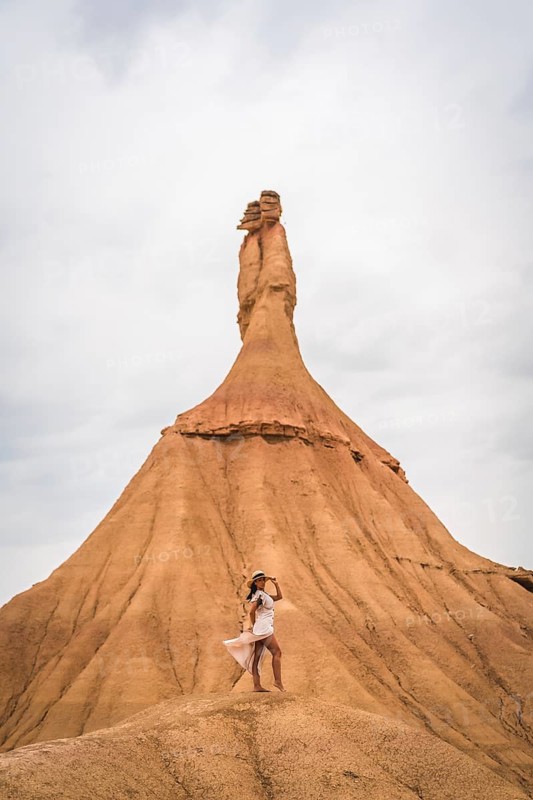 Brunette Caucasian girl with a white dress and a straw hat in the Castildetierra of the Bardenas Reales desert