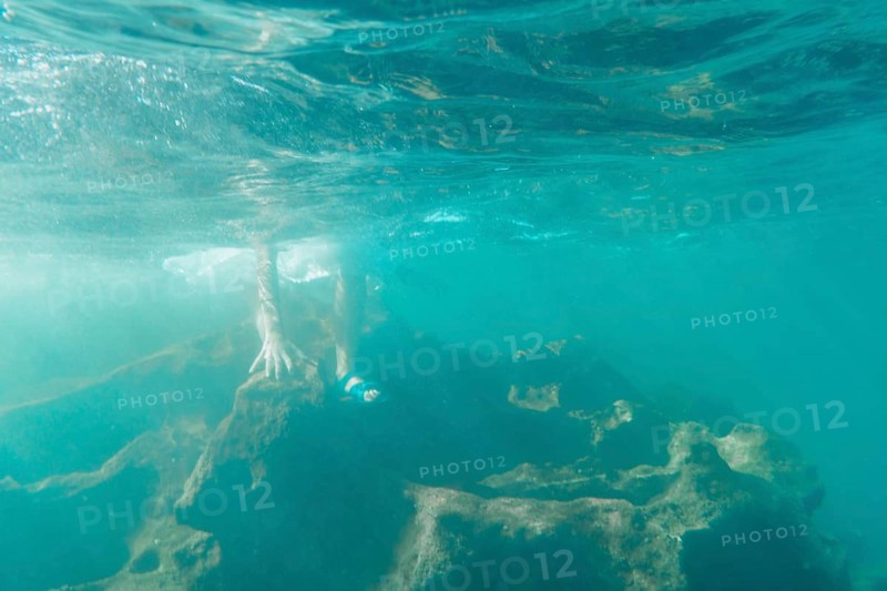 A young Caucasian brunette with flip flops getting into the water