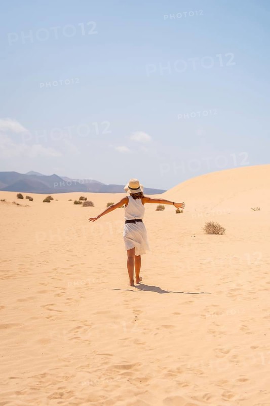 A young tourist wearing a hat walking through the dunes of the Corralejo Natural Park