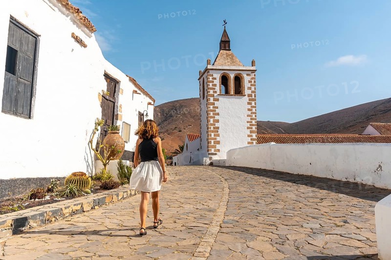 A young tourist girl walking next to the white church of Betancuria