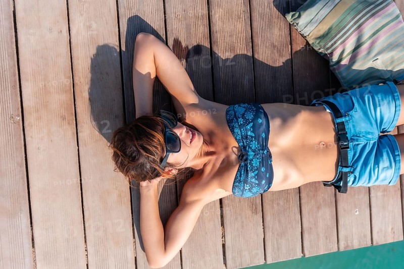 A young woman lying enjoying the holidays on the wooden walkway on the Isla de Lobos