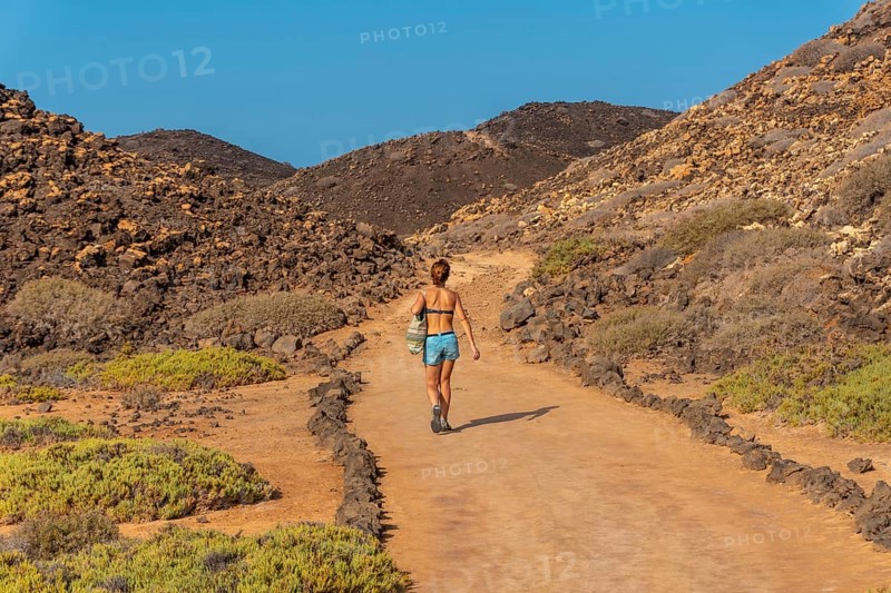 A young woman with a blue bikini on the trail to the north of the Isla de Lobos