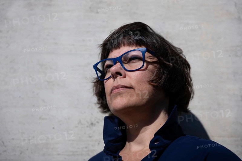 Headshot on a Elegant Woman with Eyeglasses and Leaning on a Concrete Wall in a Sunny Day in Switzerland