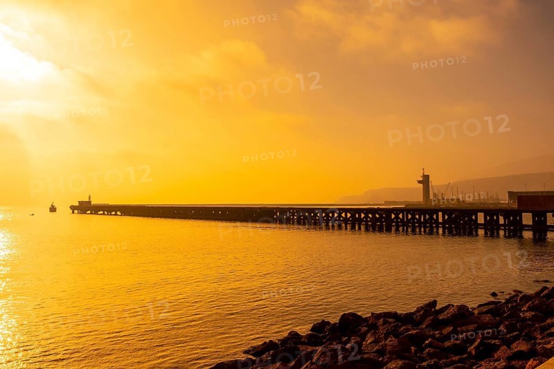 Old loading dock called Cable Frances at orange sunset on the beach of San Miguel in the city of Almeria