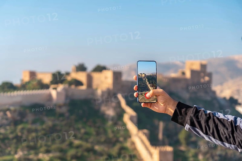 A young tourist taking a photo at the viewpoint of Cerro San Cristobal de la Muralla de Jairan and the Alcazaba in the town of Almeria