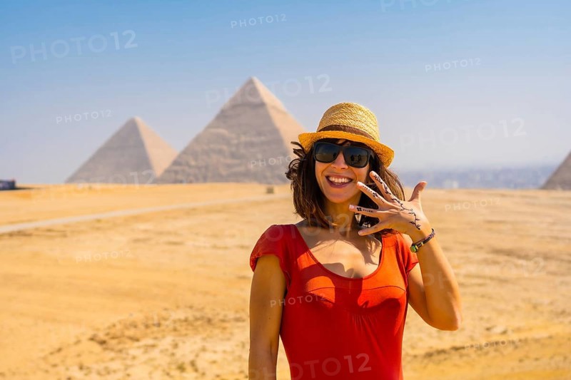 Portrait of a young tourist in red dress enjoying the pyramids of Giza