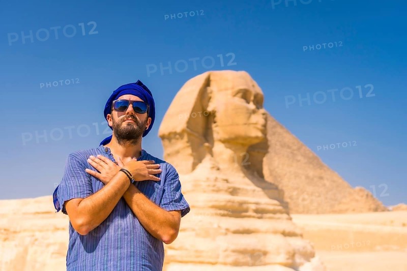 A young tourist near the Great Sphinx of Giza dressed in blue and a blue turban