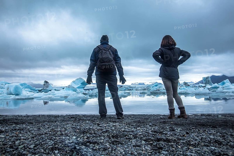 A couple with a backpack looking at the Jokulsarlon Ice Lake in the golden circle of southern Iceland