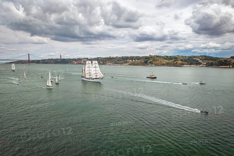 Aerial drone view of tall ships with sails sailing in Tagus river towards the Atlantic ocean in Lisbon