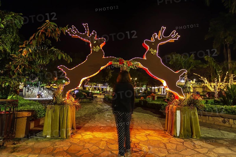 A young woman passing a reindeer arch at Christmas in Copan Ruinas. Honduras