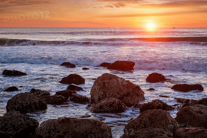 Atlantic ocean sunset with waves and rocks at Costa da Caparica