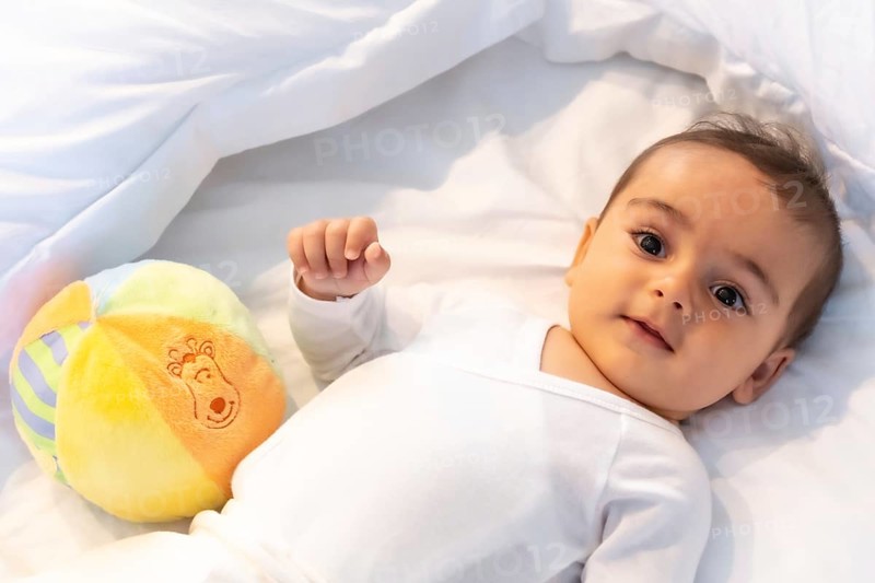 5 month old Caucasian baby smiling in white bed just woken up