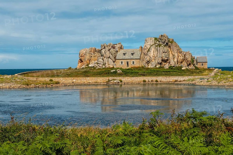 House between rocks next to a beautiful lake
