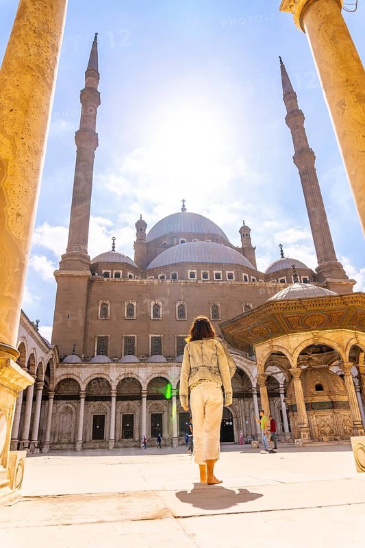 A young tourist walking in the inner courtyard of the Alabaster Mosque and the gigantic pillars in the city of Cairo