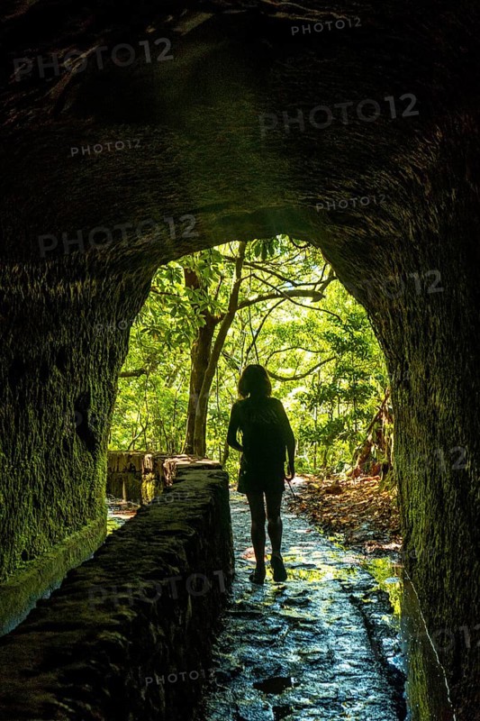 Silhouette of a young woman in the cave at Levada do Caldeirao Verde