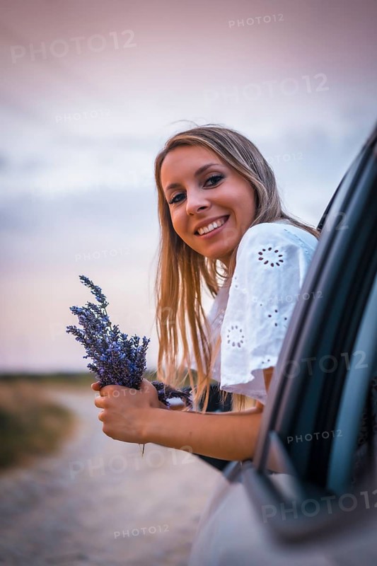 A young blonde Caucasian woman in a white dress in a lavender field. In a field of cultivation of the lavender product in Navarra