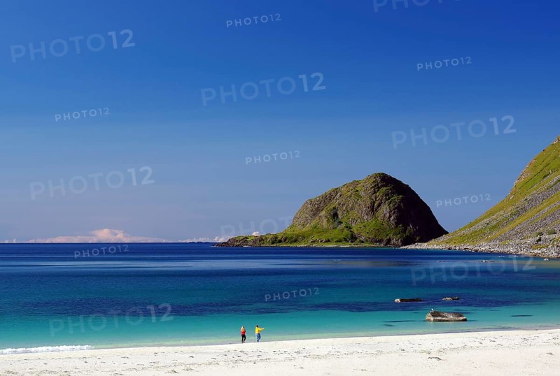 Transparent clear water with two single people on a sandy beach