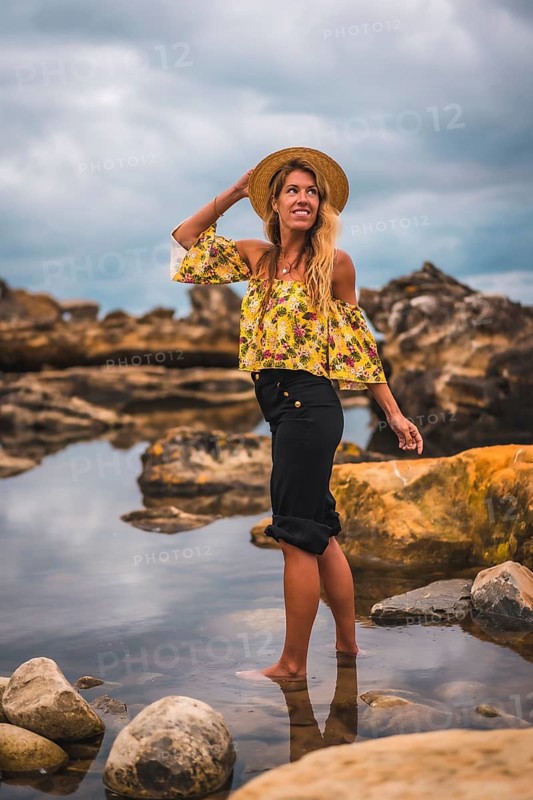 Girl in a floral shirt and black shorts in a natural landscape by the sea at sunset