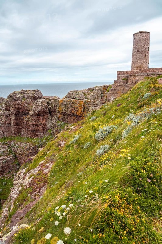 The beautiful coastline next to the Phare Du Cap Frehel is a maritime lighthouse in Cotes-dÂ´Armor France . At the tip of Cap Frehel