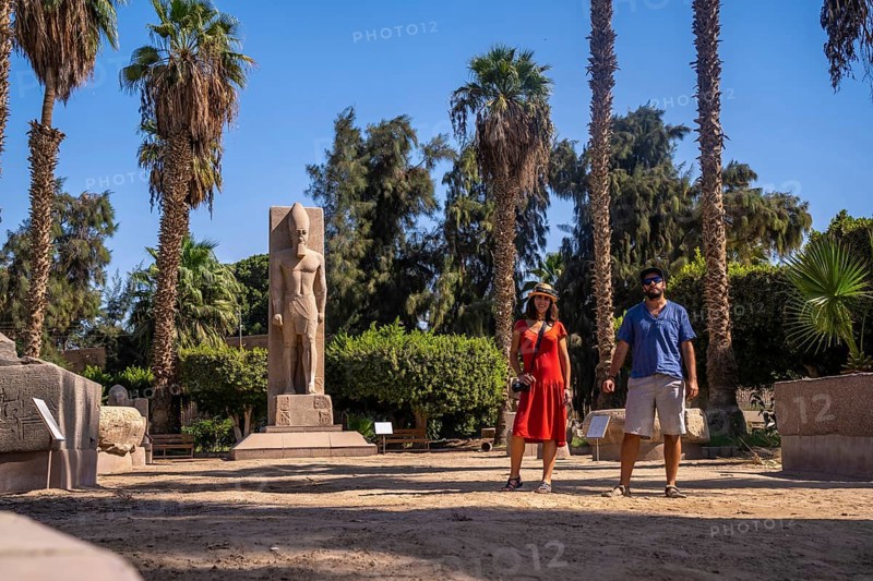 A tourist couple visiting the sculpture of Pharaoh Ramses II at Memphis in Cairo