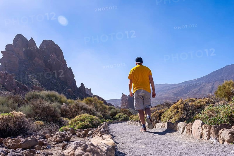 A tourist walking on the path between Roques de Gracia and Roque Cinchado in the natural area of Teide in Tenerife