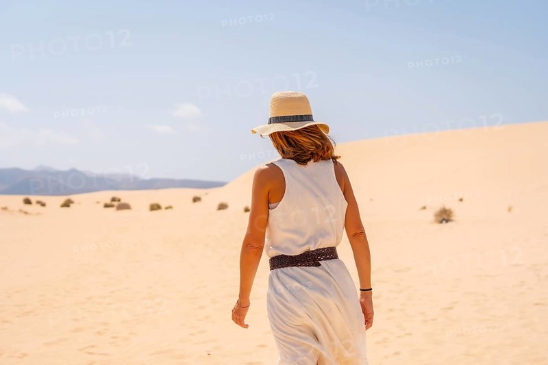 A young tourist wearing a hat walking along the sand on the beaches of the Corralejo Natural Park