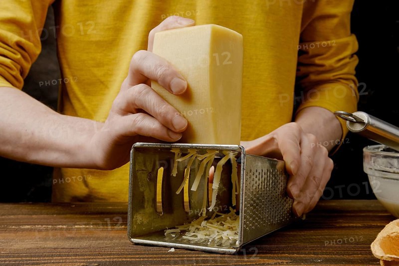 Unrecognizable man shredding cheese with metal grater