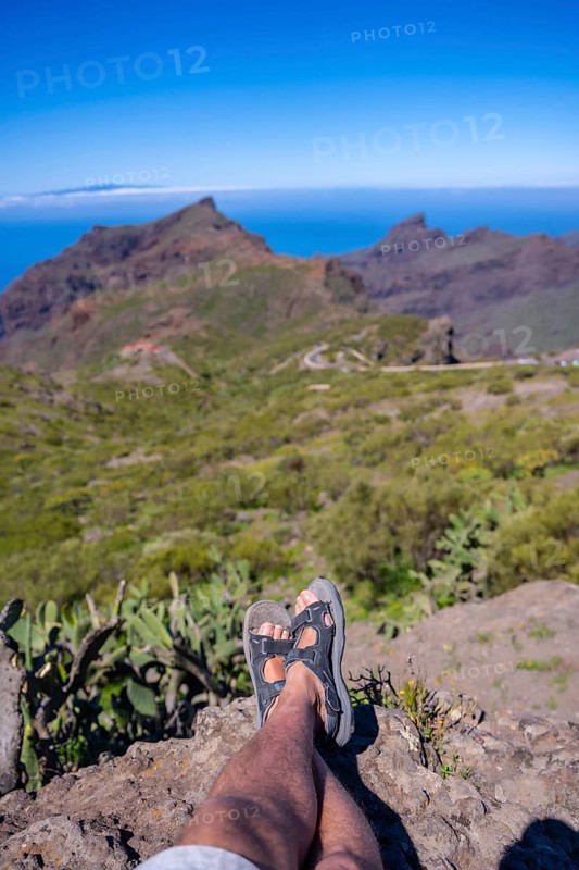A young man sitting looking at the mountain town of Masca in the north of Tenerife