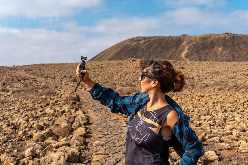 A young woman making a video next to the Crater of the Calderon Hondo volcano near Corralejo