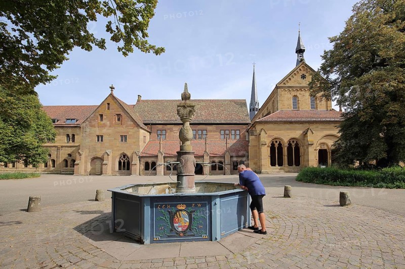 Romanesque monastery church and fountain with coat of arms of Wuerttemberg Duke Ludwig