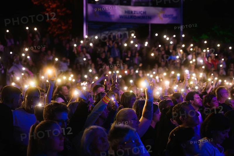 Crowd with mobile phone lights at Live Klostersommer Festival in Historic Monastery