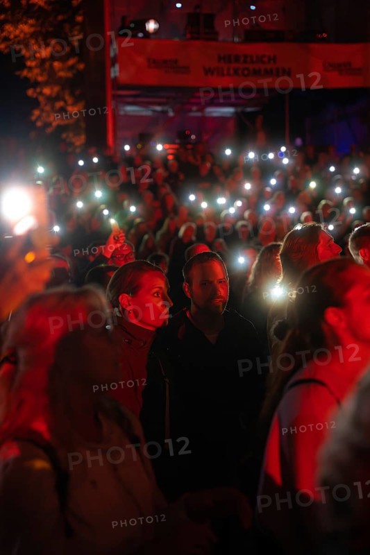 Crowd with mobile phone lights at Live Klostersommer Festival in Historic Monastery