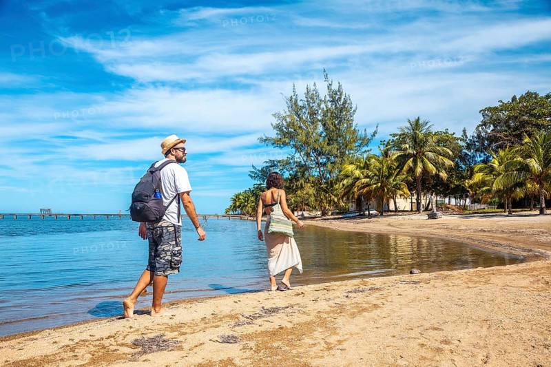 Two young people walking along the beach of Sandy Bay on Roatan Island. Honduras