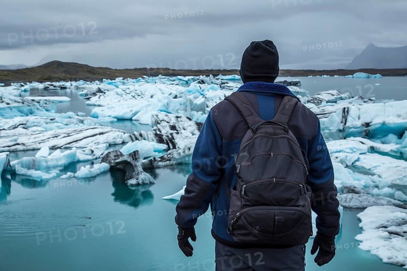 A young tourist with backpack on the frozen lake of Joekulsarlon in August. Iceland