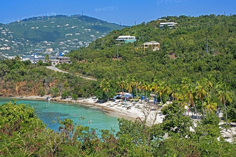 Tourists on white sandy beach with palm trees along Druif Bay at Water Island