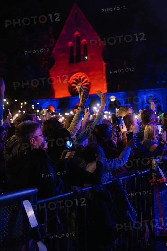Crowd with mobile phone lights at Live Klostersommer Festival in Historic Monastery