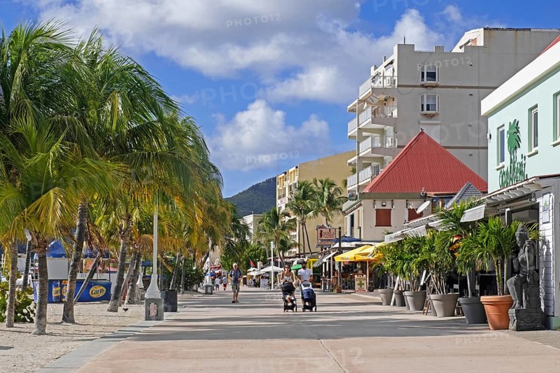 Tourists walking on boulevard with palm trees along the beach in capital city Philipsburg of the Dutch island part of Sint Maarten in the Caribbean