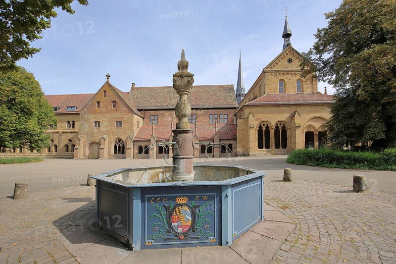 Romanesque monastery church and fountain with coat of arms of Wuerttemberg Duke Ludwig