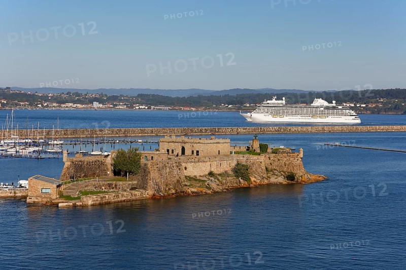 Historic fortress Castle San Anton at the harbour entrance and cruise ship Seven Seas Splendor leaving port