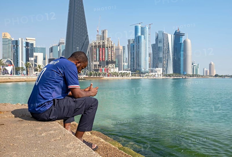 Man sits on steps of Corniche with skyscrapers in background