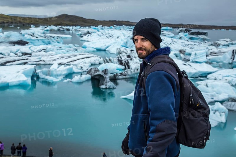A young man with a backpack looking at the Jokulsarlon Ice Lake in the golden circle of southern Iceland
