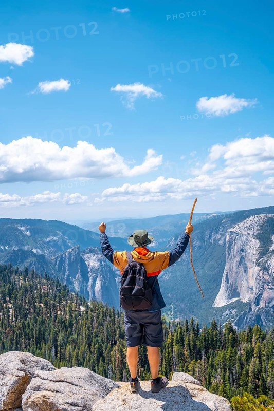 A young man with a walking stick and arms raised at Sentinel Dome in Yosemite National Park. United States